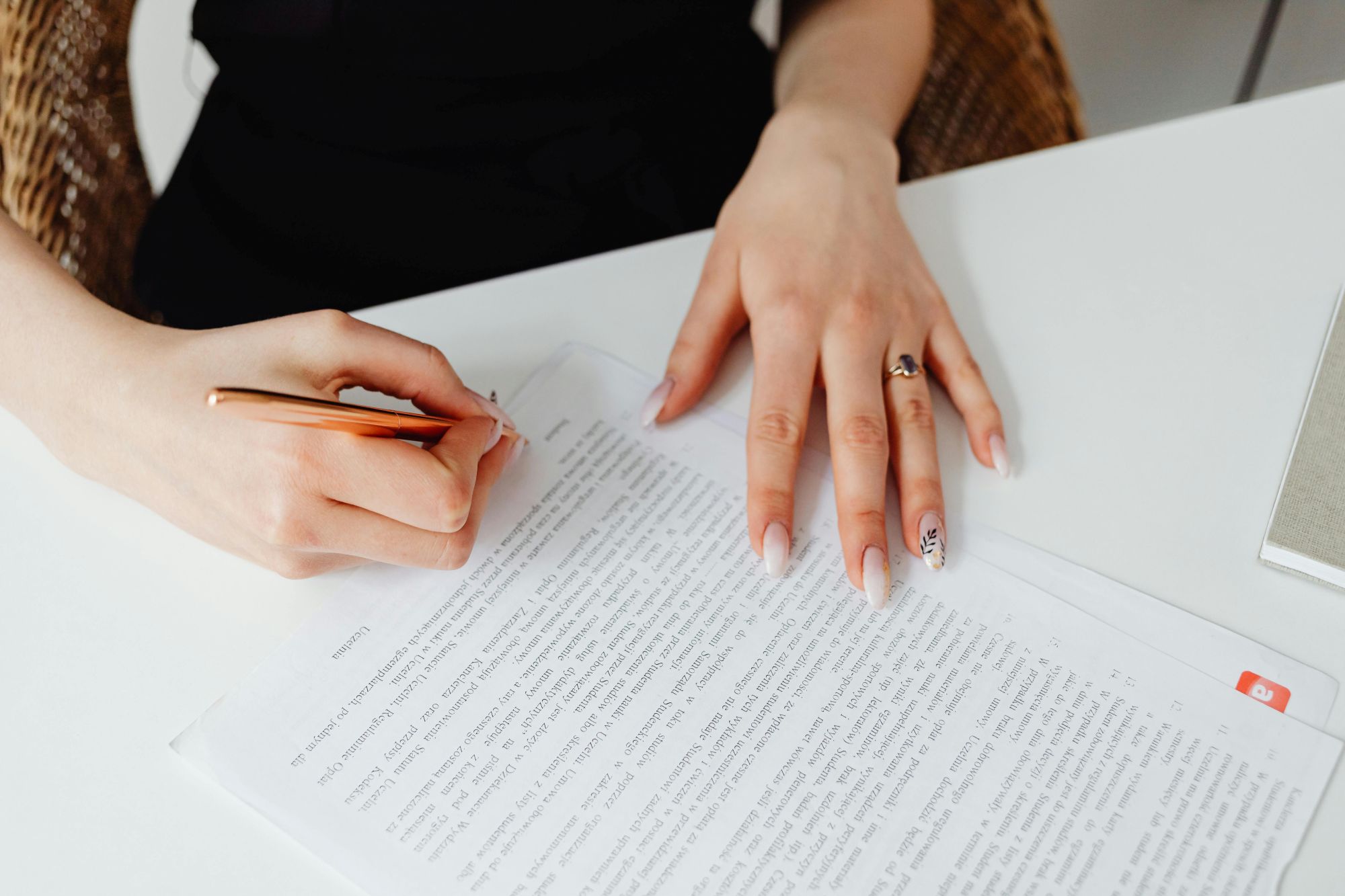 person holding pen writing on a document